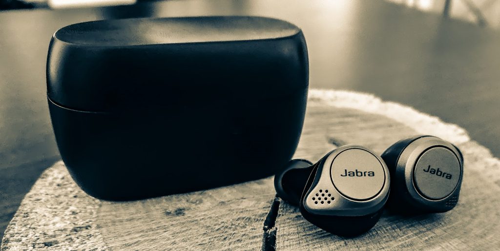 Die Jabra Elite 75t Kopfhörer inklusive Ladeschale auf einem hölzernen Untergrund